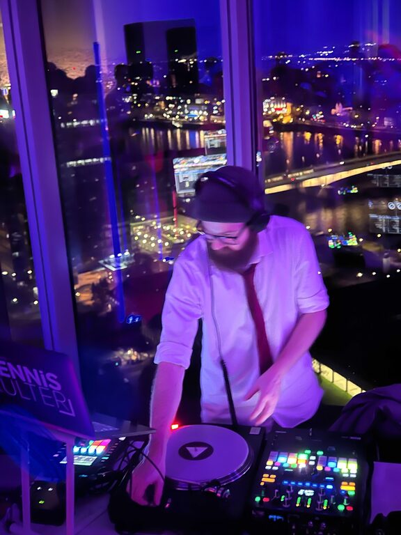 Hochzeits-DJ Dennis Külter am Plattenspieler mit Kölner Skyline im Hintergrund